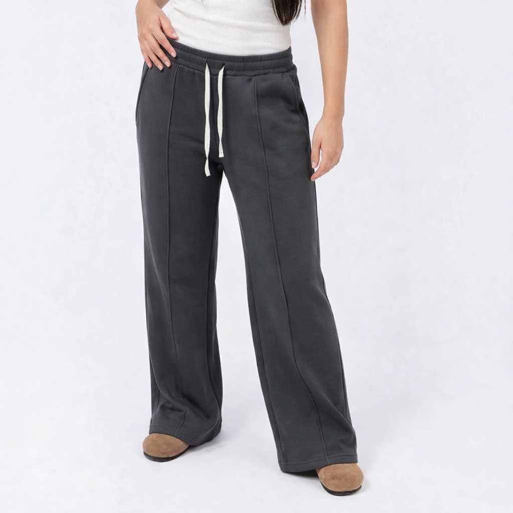 Person wearing dark gray wide-leg pants with a white background