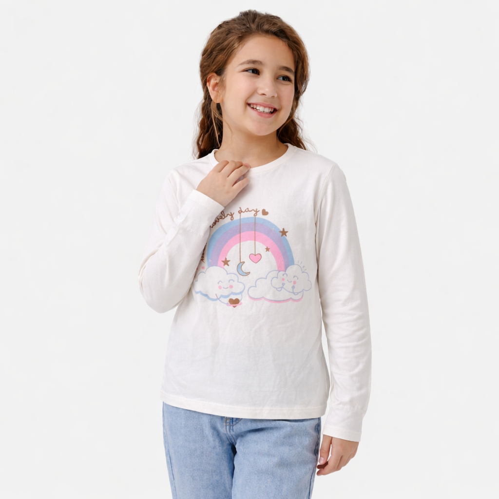 Young girl wearing a white long-sleeve shirt with a rainbow and cloud design on a plain background