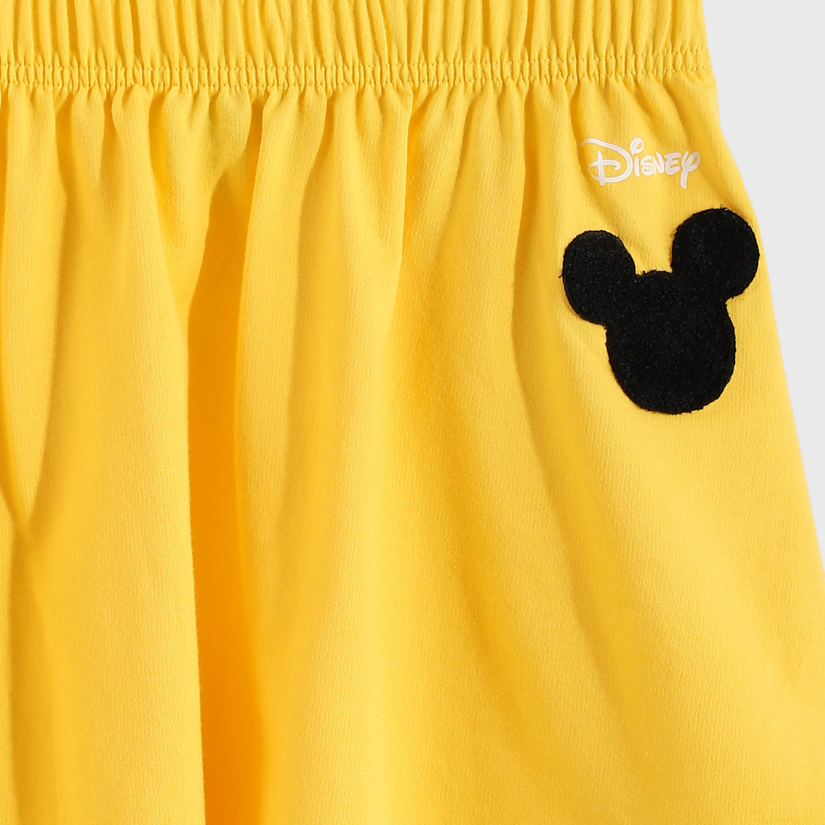 Yellow shorts with a black Mickey Mouse ears design and Disney logo on a white background