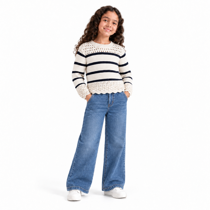 Girl wearing cream striped knit pullover with blue jeans on white background