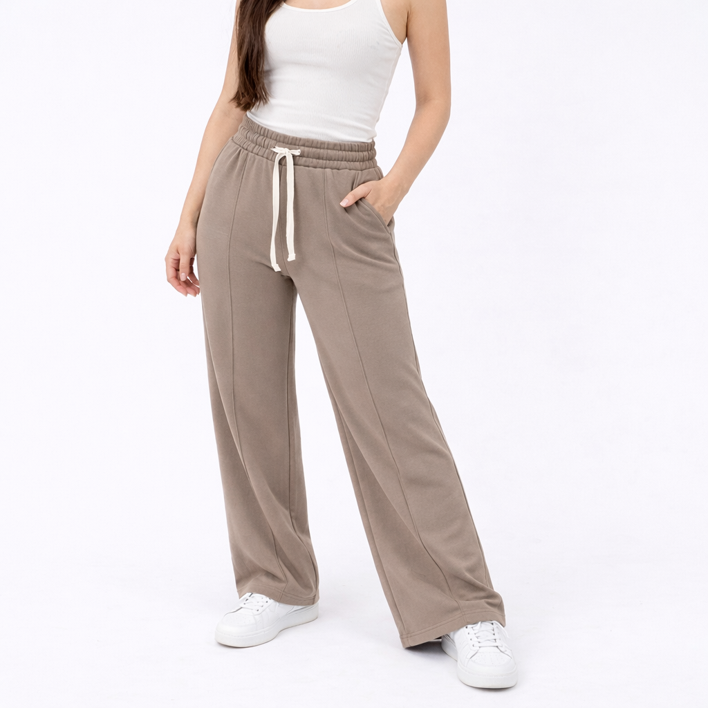 Person wearing beige wide-leg pants and a white tank top on a white background