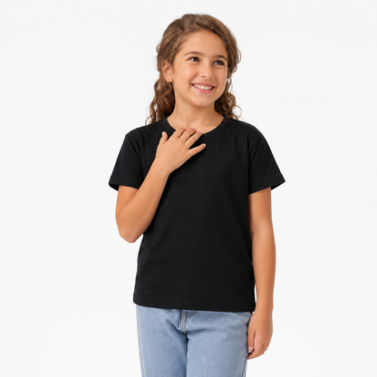 A young girl with wavy brown hair smiling and posing in a plain black short-sleeve t-shirt and light blue jeans against a solid white studio background.