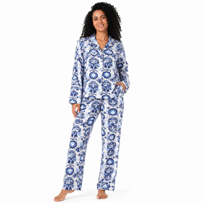 A woman modeling a two-piece pajama set with a blue and white floral pattern, standing against a plain white background.