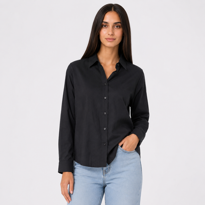 A woman modeling a black long-sleeve button-up shirt with light blue jeans against a plain light gray studio background.