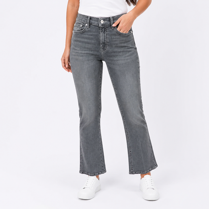 A model wearing a pair of dark gray, straight-leg flared jeans with a faded wash, paired with a white t-shirt and white sneakers, shown from the waist down on a light gray studio background.