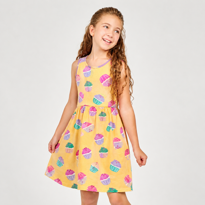 Young girl wearing a yellow dress with cupcake pattern on a white background