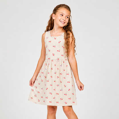 Young girl wearing a sleeveless dress with cherry pattern on a plain background