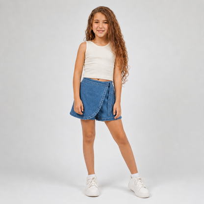Young girl wearing a white sleeveless top and blue denim skirt on a light gray background