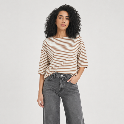 Woman wearing a striped shirt and jeans on a plain background
