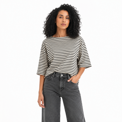 Woman wearing a black and white striped shirt and gray jeans on a white background