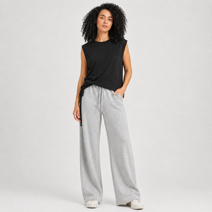 Woman wearing a black sleeveless top and gray wide-leg pants on a white background