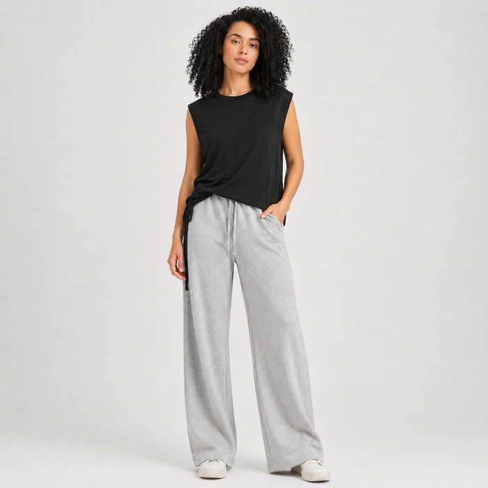 Woman wearing a black sleeveless top and gray wide-leg pants on a white background