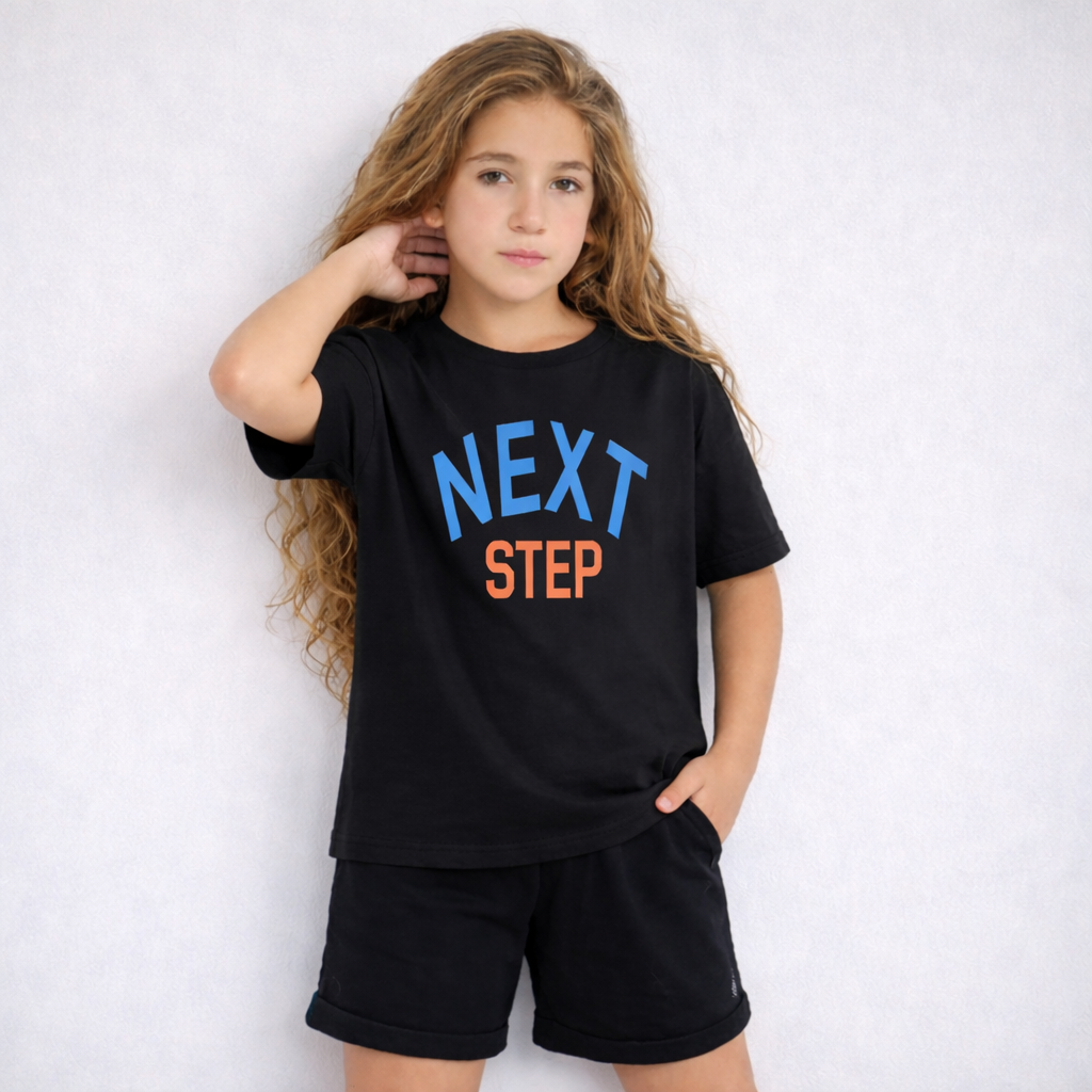 Young girl wearing a black t-shirt with 'NEXT STEP' text on a white background