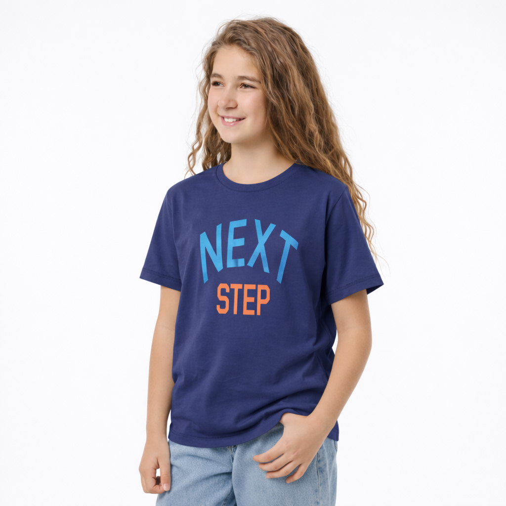 Young girl wearing a blue t-shirt with 'NEXT STEP' text on a white background