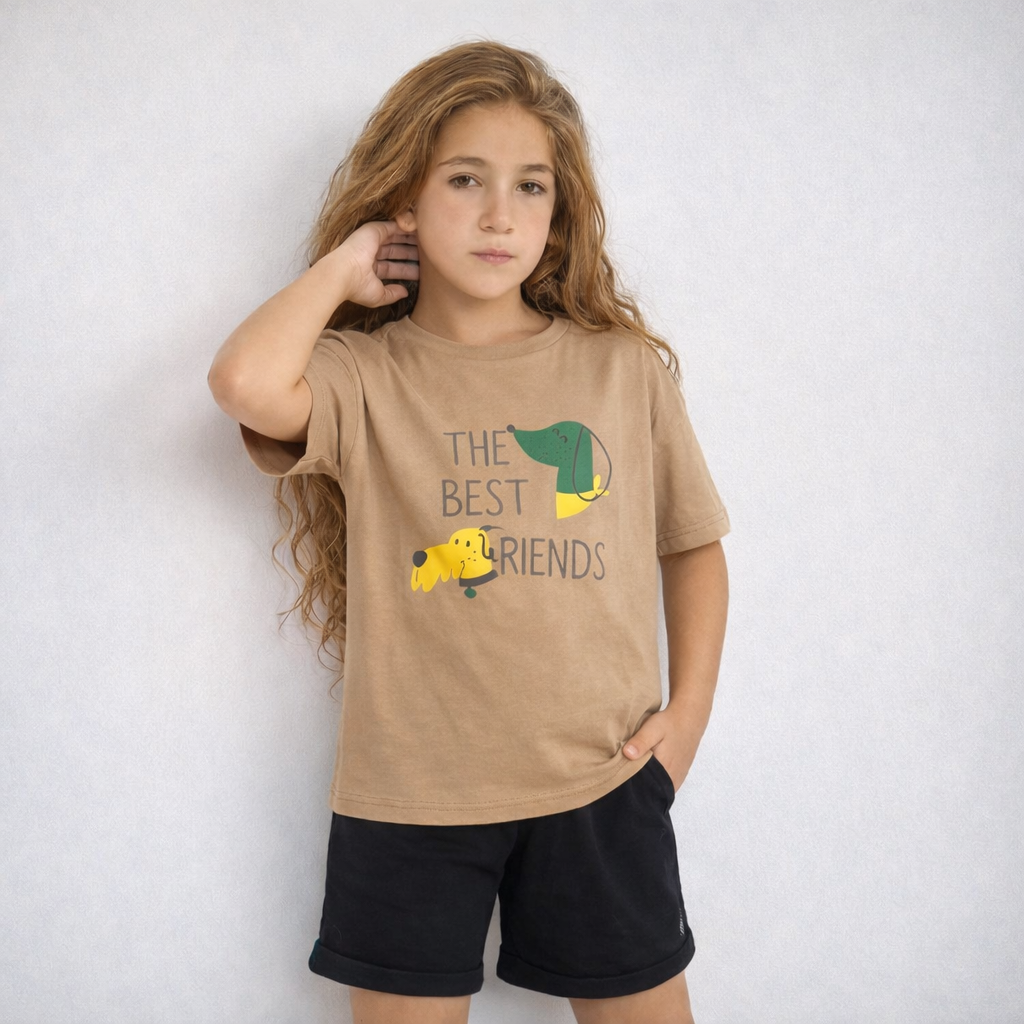 Young girl wearing a beige t-shirt with a graphic and text, standing against a white background