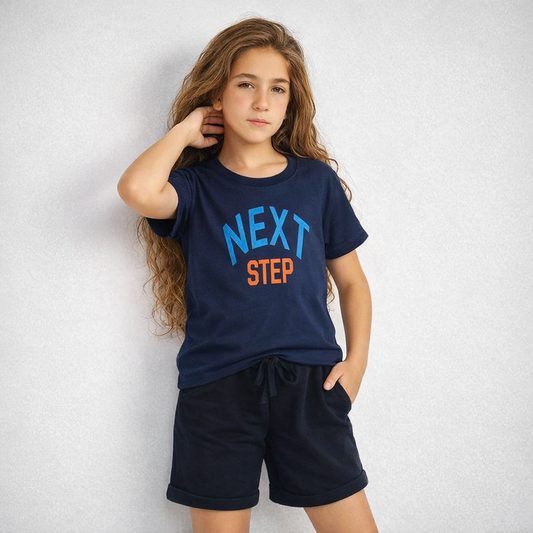 Child wearing a navy blue t-shirt with 'NEXT STEP' text on a white background
