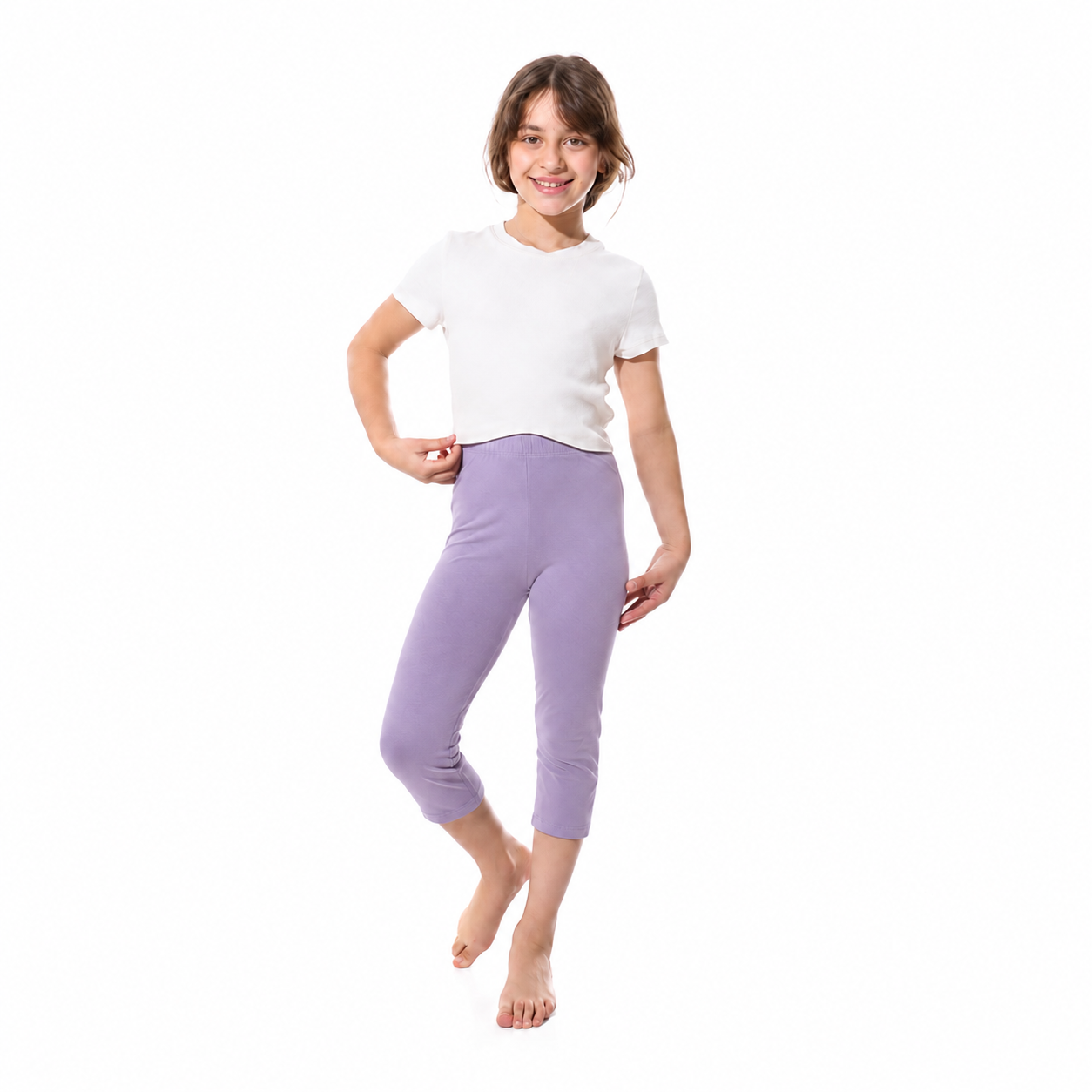 A young girl modeling a white short-sleeve t-shirt and lavender purple cropped leggings against a plain white background.