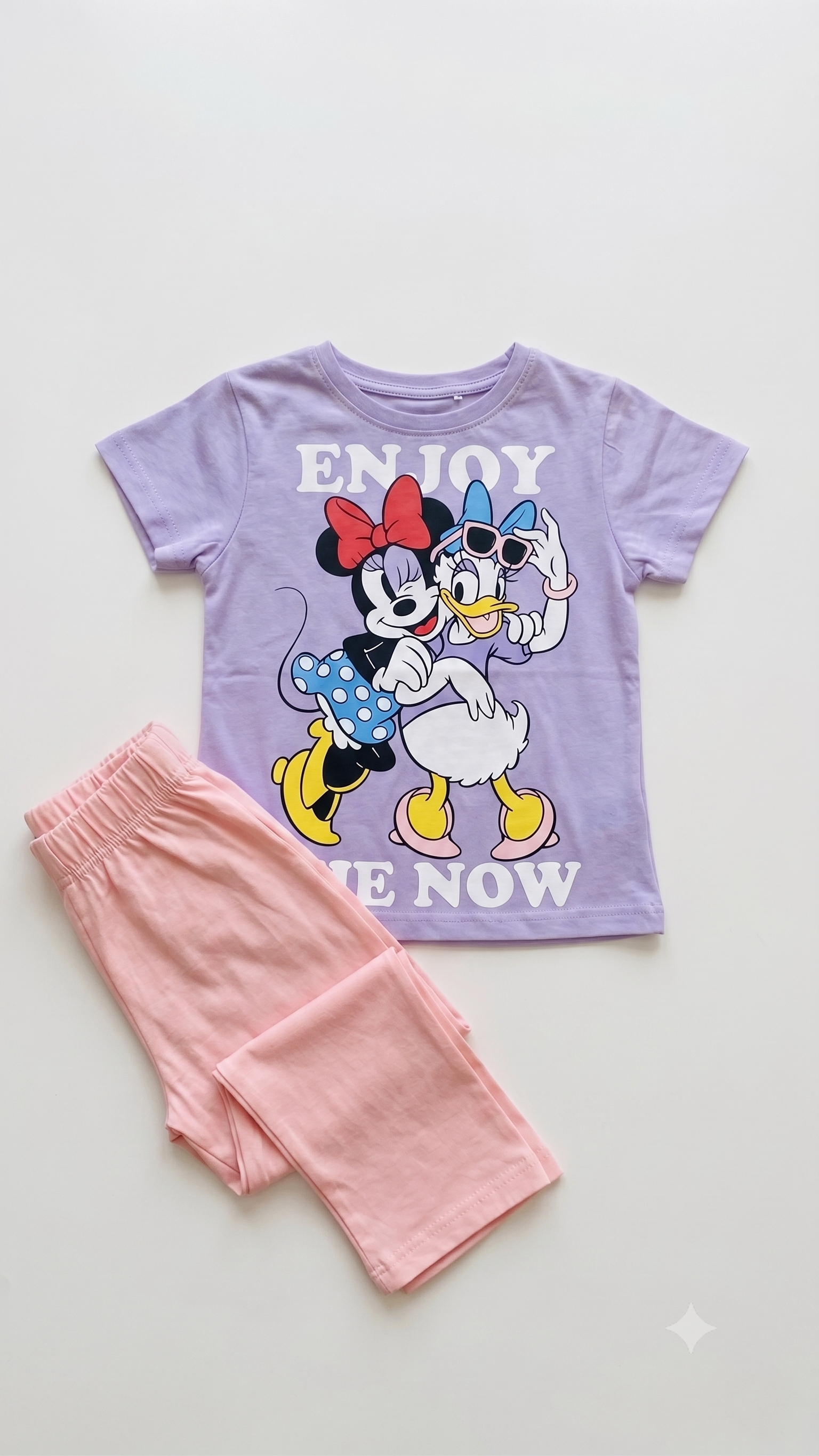 Children's t-shirt with cartoon characters and pink pants on a light gray background
