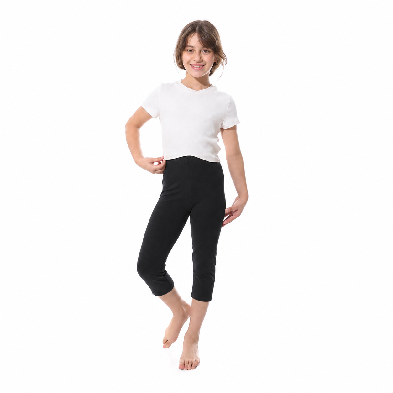 A young girl modeling black cropped leggings and a white t-shirt against a solid white background.
