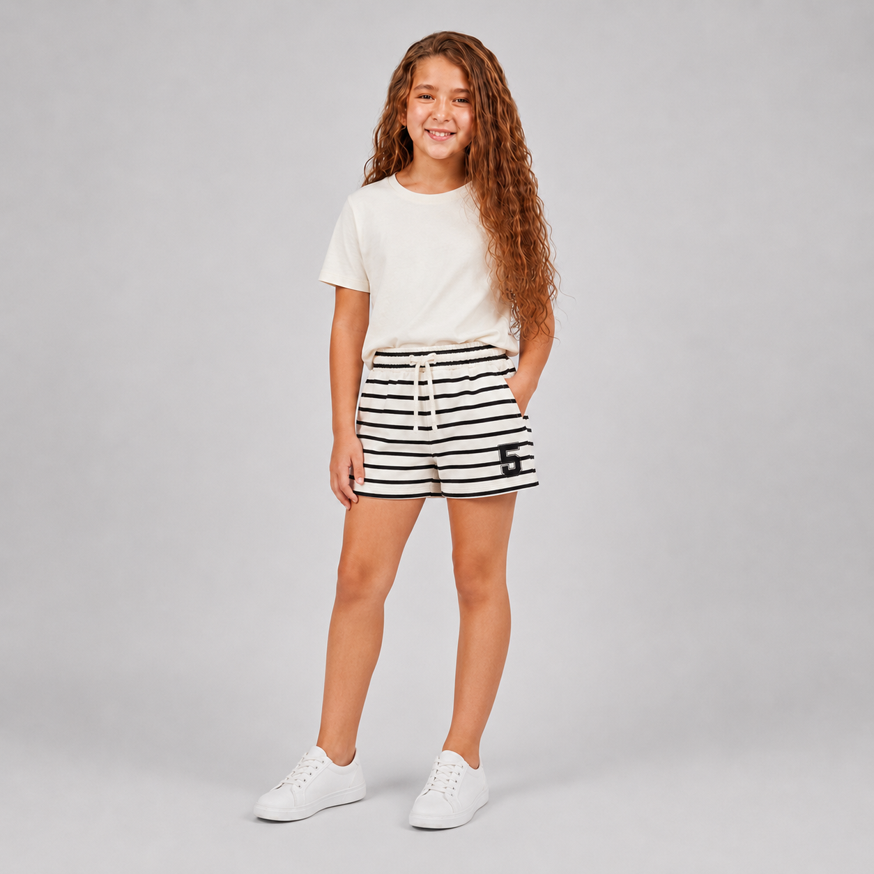 Girl wearing cream and black striped drawstring shorts with number 5 patch