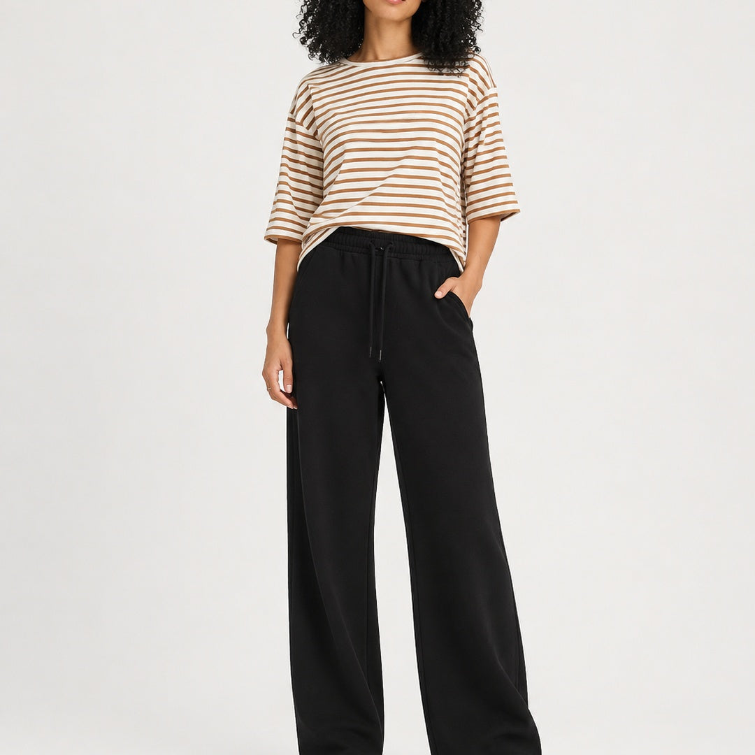 Person wearing a striped shirt and black pants on a white background