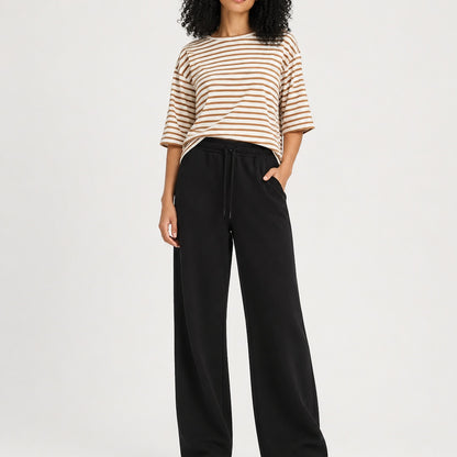 Person wearing a striped shirt and black pants on a white background